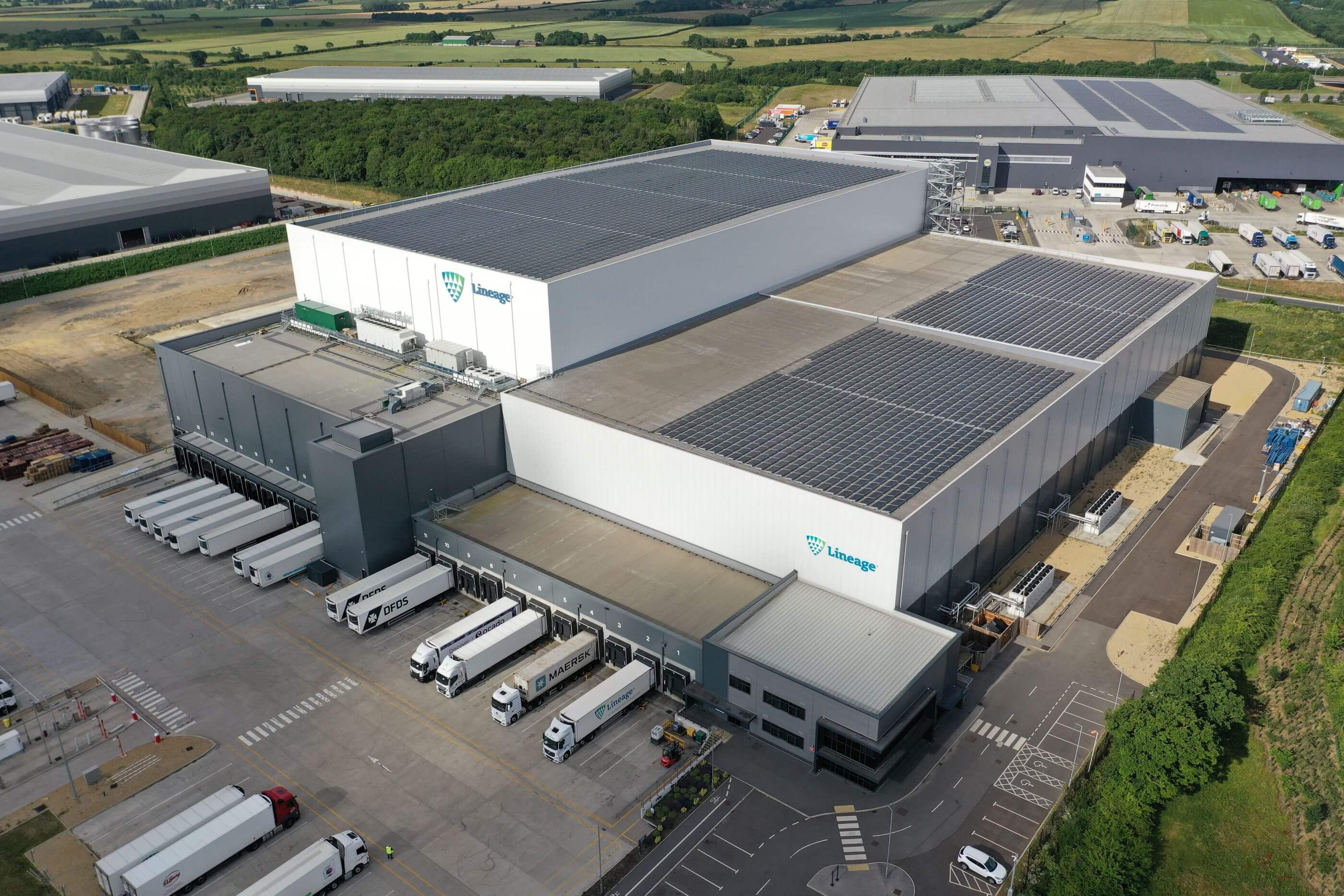 Exterior drone shot of Lineage's Peterborough cold storage warehouse in the UK, showcasing the large facility and rooftop solar panel array.