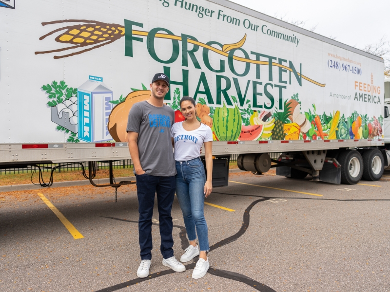 Detroit Lions quarterback Jared Goff and his fiancé, Christen Harper, stand in front of a Forgotten Harvest semi trailer at food donation event benefitting Detroiters