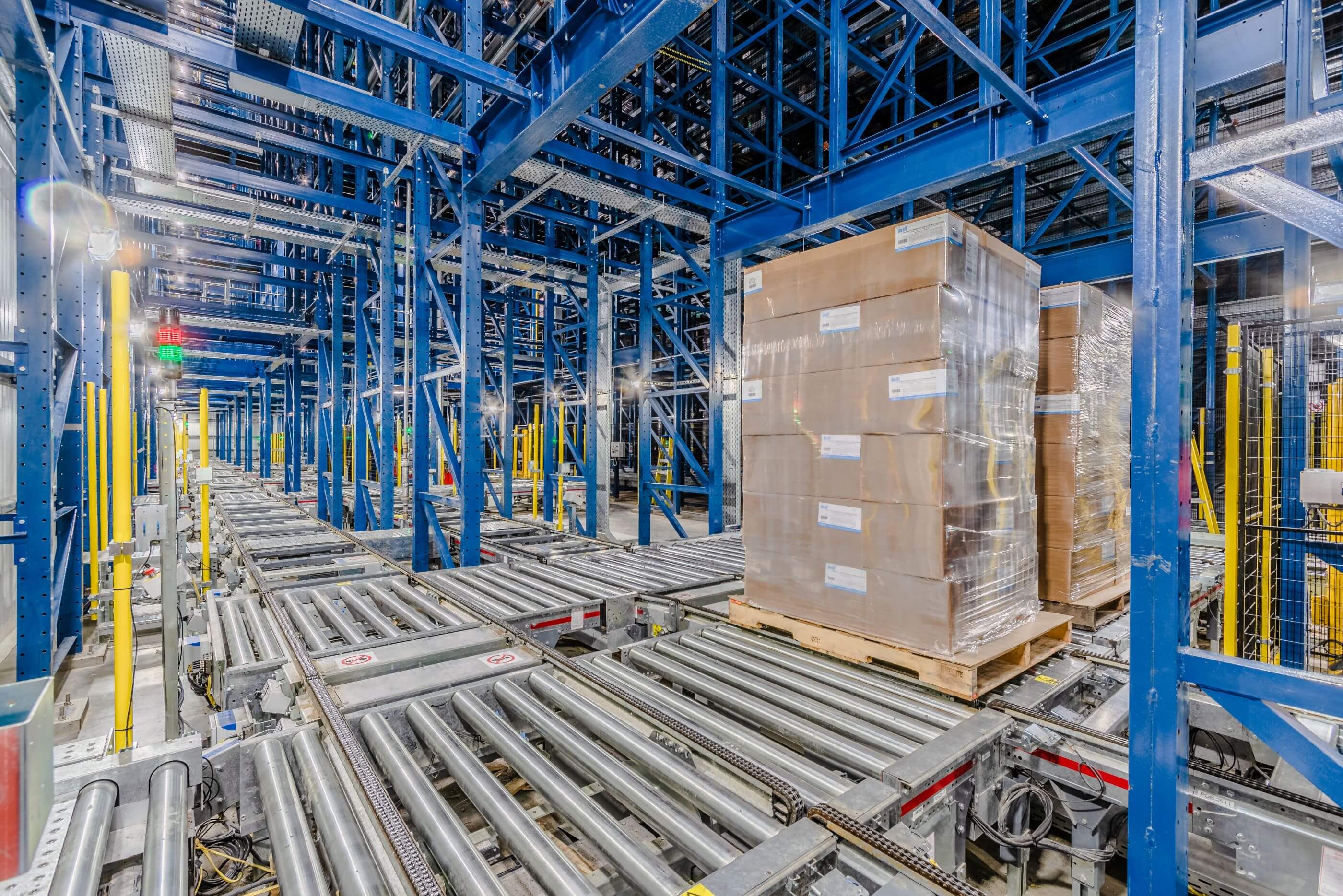 Lineage Sunnyvale automated warehouse interior with conveyor belts transporting shrink-wrapped pallets, flanked by tall blue steel racks.