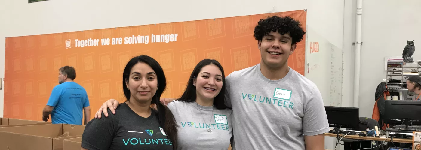 Three Lineage volunteers pose for a photo while working in a food bank